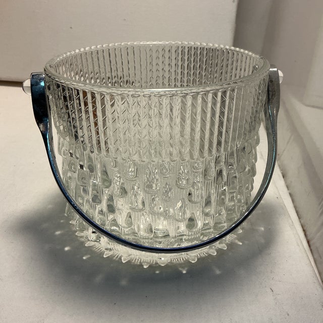 The Mid-Century Glass and Chrome Ice Bucket is a stylish and elegant accessory perfect for any occasion. Made exclusively...
