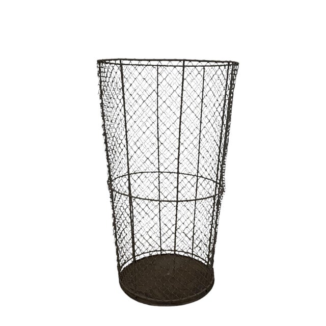 This vintage wire mesh metal trash can features a tapered cylindrical form with an open top and a solid circular metal...