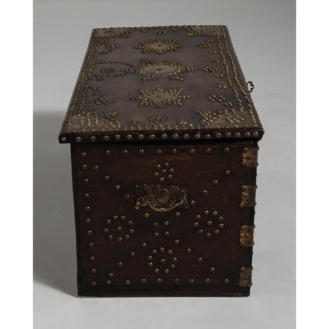 A decorative chest featuring brass detailing that enhances its visual richness. The piece combines storage with historical...