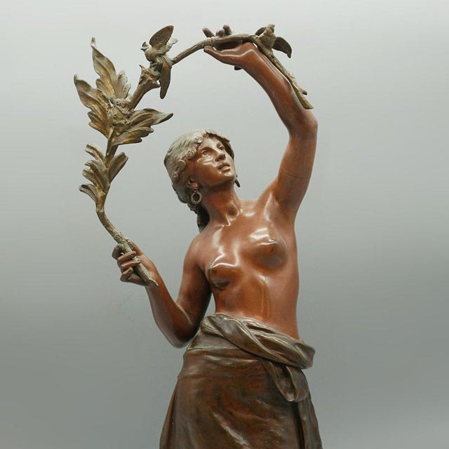 A late 19th century bronze sculpture of a scantily clad lady holding a branch with birds perched upon it. With a shawl...