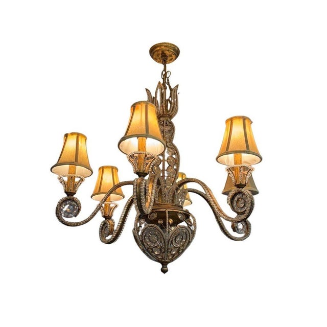 Elegant and timeless, this vintage 1960s Regency chandelier features six gracefully scrolling arms crafted in gilt iron...