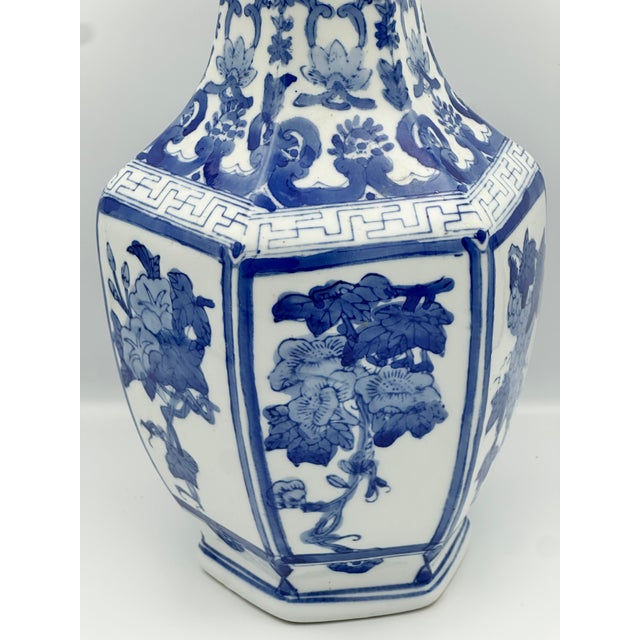 A beautifully hand painted chinoiserie blue and white porcelain vase featuring a hexagonal form, stylized cobalt floral...
