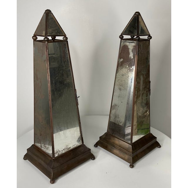 Antique mirror obelisks with metal pedestal base. Obelisks feature a hidden hinged door at one side for the insertion of...