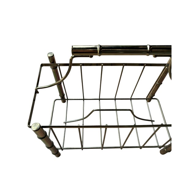 A polished brass magazine rack in the faux-bamboo style that never really left — segmented posts, a graceful arched...