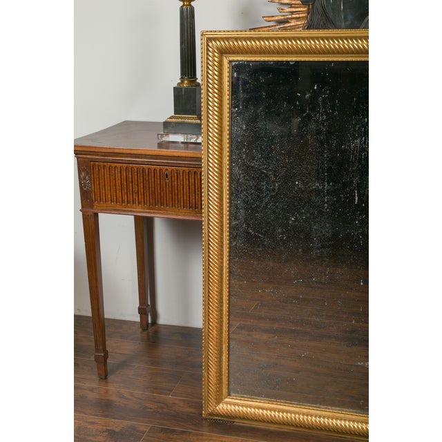 A French giltwood rectangular mirror from the early 20th century, with twisted motifs. Created in France during the turn...