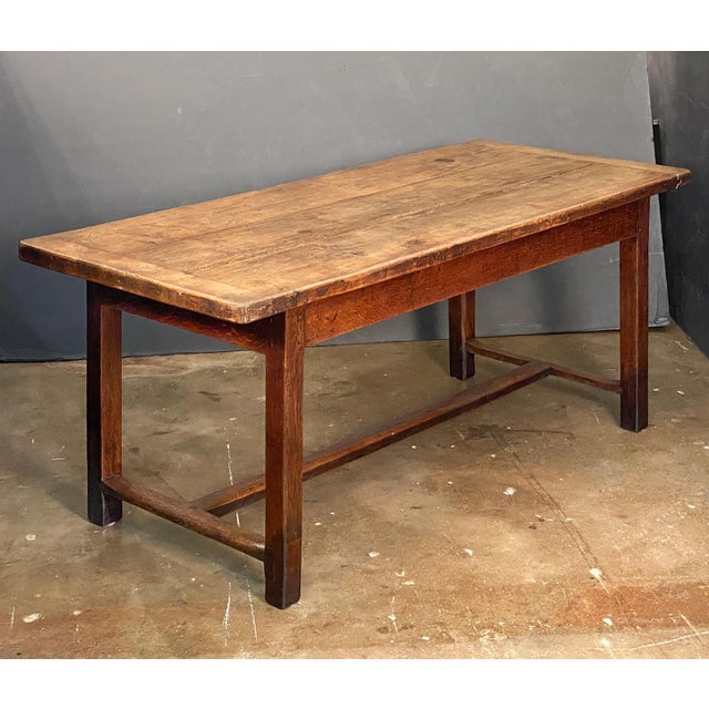 A large English rectangular farmhouse or refectory table of fine patinated oak, featuring a handsome plank top set upon a...