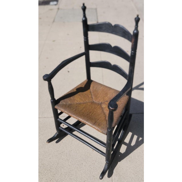 19thc Original black painted ladder back rocking chair with paddle arms.This chair is strong and sturdy...