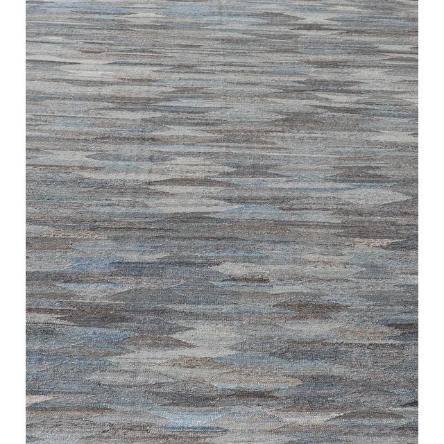 Measures: 9'0 x 11'7. This flat-weave tribal kilim has been hand-woven. The rug features a modern solid/diamond design,...