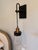 Striking pair of hanging wall sconces combining blackened metal, warm antique brass accents, and clear glass shades. Each...