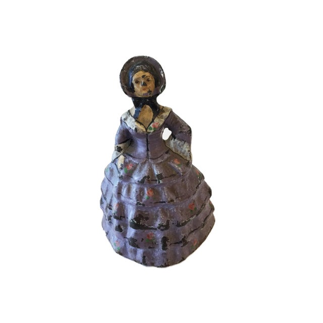 An old heavy one piece of cast iron door stop depicting the figure of a young women dressed in a victorian purple dress,...