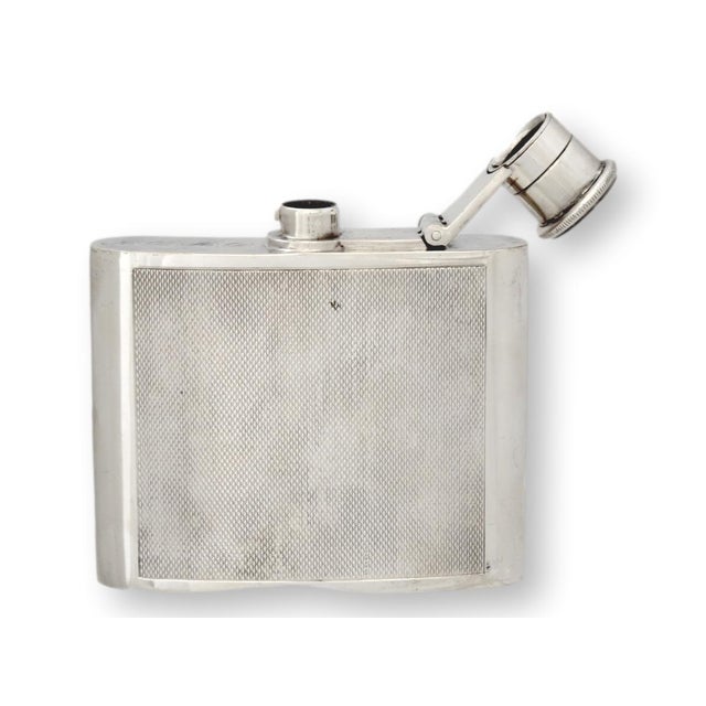 An English mid-century silverplate hip flask with classic engine-turned guilloché panels and a curved body for pocket...