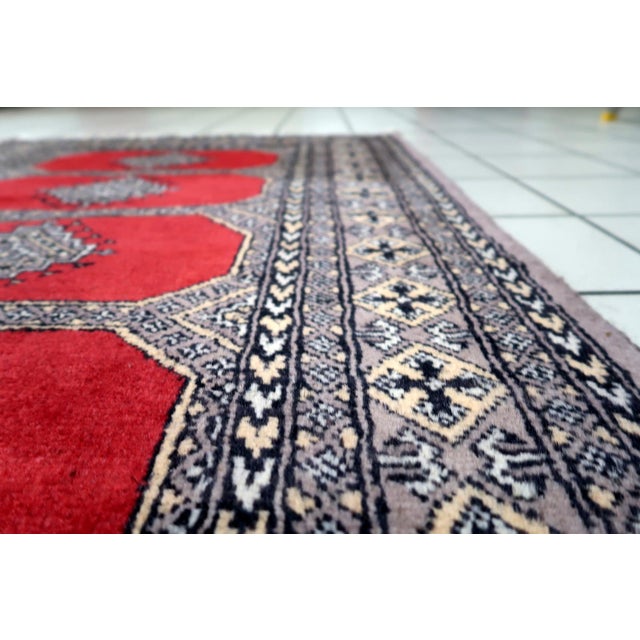 A handmade vintage Uzbek Bukhara rug from the 1960s, woven in wool and displaying the iconic Tekke-influenced Bukhara...