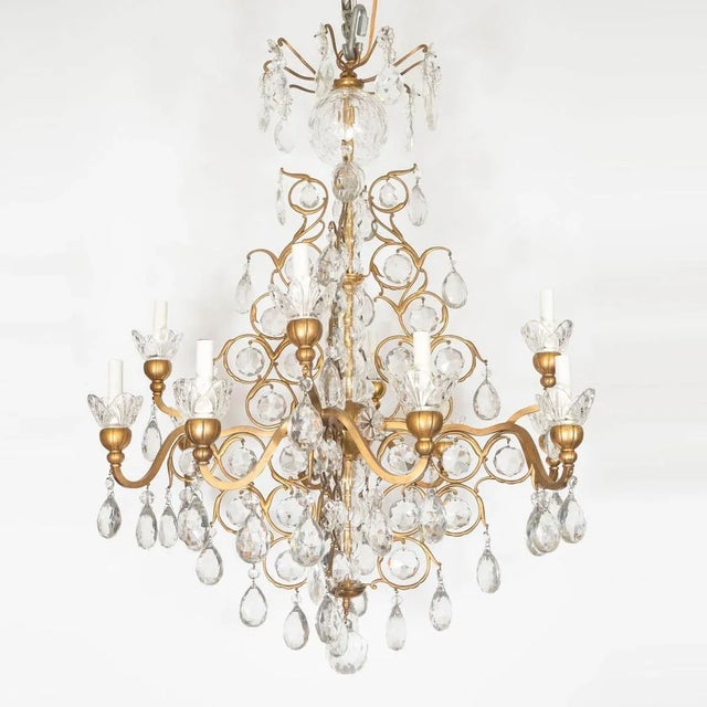 Traditional gilt metal chandelier with curvilinear tendril motif and crystal drop elements. Origin: United States Circa:...