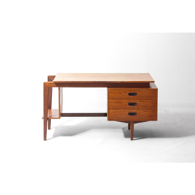 A striking writing desk from the 1960s featuring a wide writing top, three drawers and a geometric book shelf to the side.