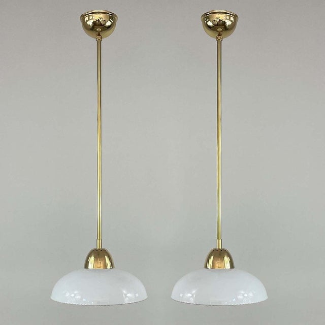 These elegant pendants were designed and manufactured in Sweden in the 1940s. The lights feature white opaline glass...