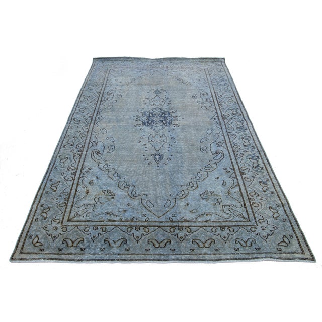 This vintage overdyed Persian wool rug features a captivating blue and gray color field with charming black floral...