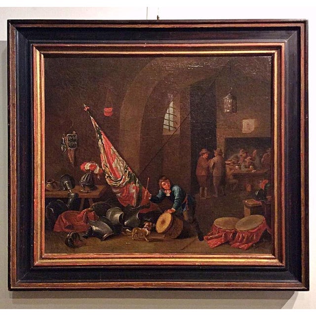 The scene depicts a tavern interior with resting soldiers enjoying a convivial moment in the background, while the...