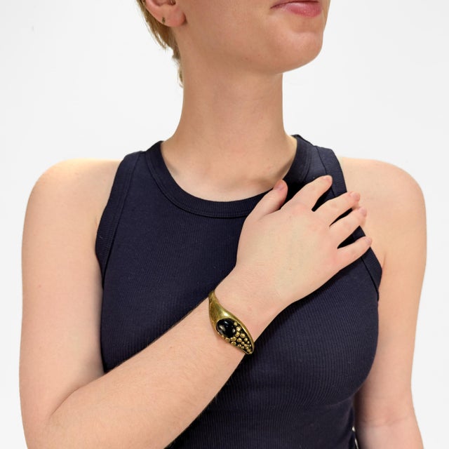 A fine, signed Brutalist cuff bracelet. In cast brass. Attributed to Stephen Burr. With a bezel-set banded agate cabochon....