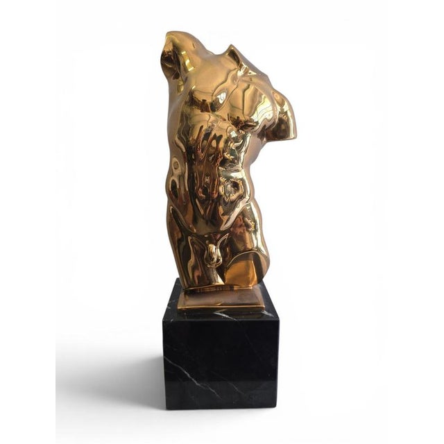 Elegant male torso sculpture in solid gilt bronze, created in Italy during the 1950s and mounted on a refined black marble...