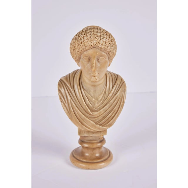 A petite 19th c. hand-carved alabaster bust of Empress Domitia Longina (c. 50-126, CE) in an elaborate hairstyle of the...