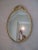 Elegant oval shaped gold mirror with ornate detail. Hanging hardware attached.