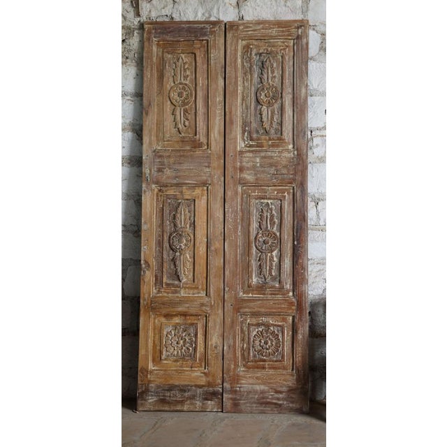 A stunning pair of antique French doors featuring intricate hand-carved floral motifs and a beautifully aged distressed...