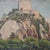 This mid-20th century French fortress painting presents a commanding yet contemplative view of historic architecture set...