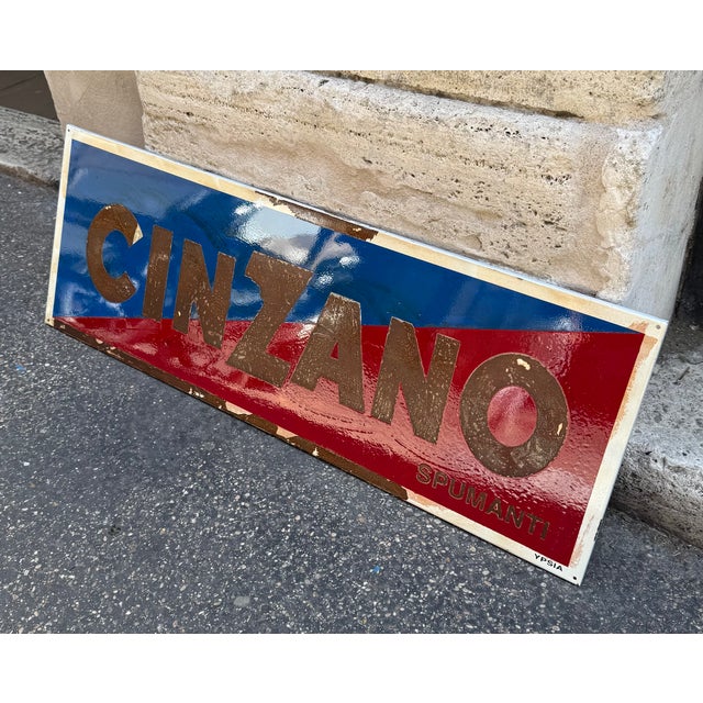 Authentic Cinzano enamel advertising sign, featuring the famous two-tone blue and red graphic with embossed lettering. An...