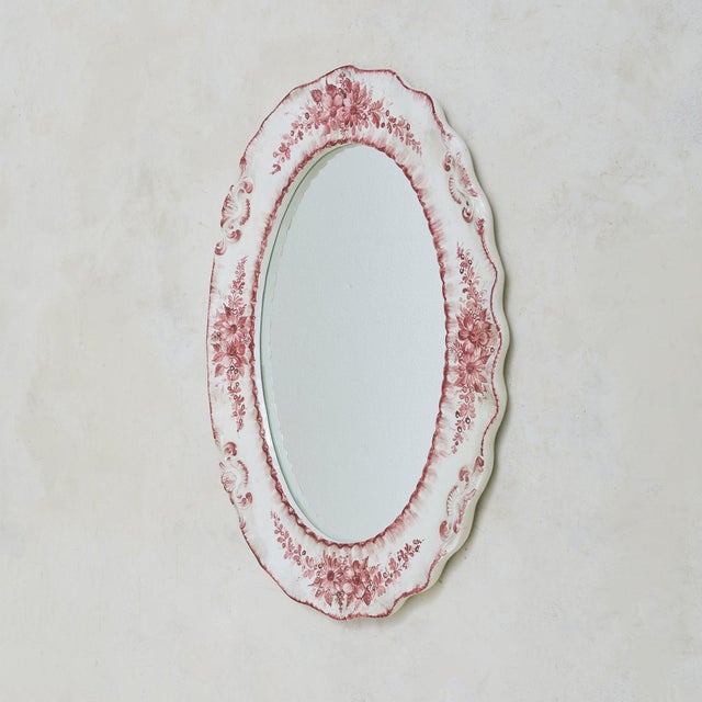 An Italian hand-painted ceramic wall mirror by Bassano, dating to the mid-20th century. The oval frame is sculpted in...