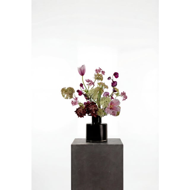 A bold, tonal arrangement built around burgundy hydrangea, purple tulips, and soft lilac accents. The deeper palette is...