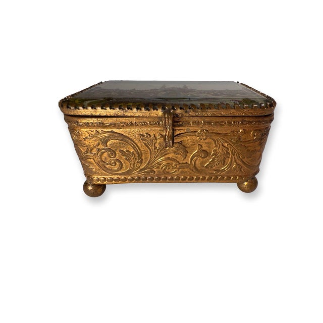 A refined antique French souvenir jewelry box dating to the late 19th century, crafted in gilt brass and topped with a...