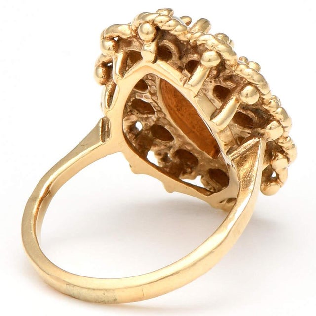 The centerpiece of this 14K yellow gold, mid-century modern ring is a large, marquise-shaped, coral stone showcased by a...