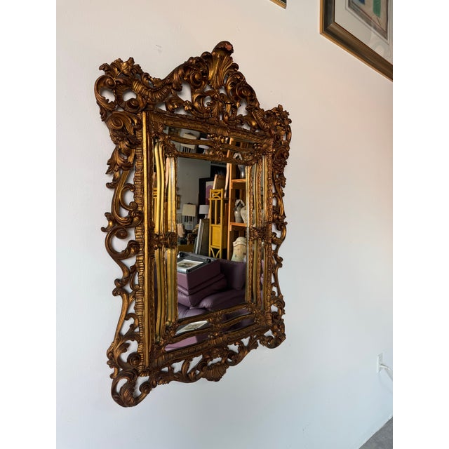 A stunning and ornate 1960s vintage Italian wall mirror in the Hollywood Regency style. This highly decorative piece...