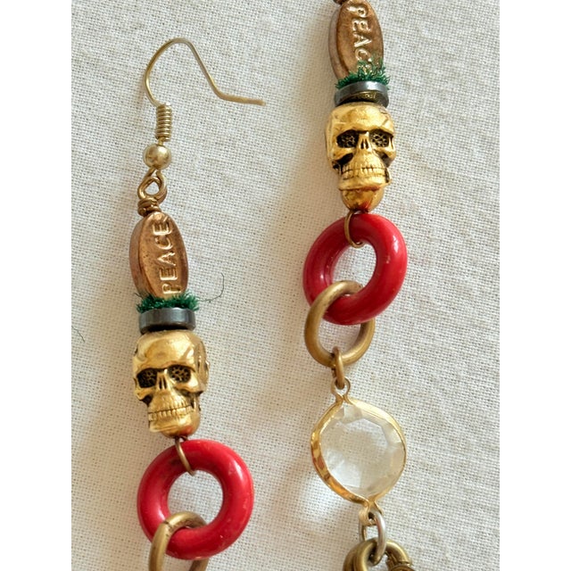 Vintage 1990s gothic tribal shoulder duster earrings featuring an eclectic vertical arrangement of cast metal, glossy red...