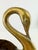 A sculptural vintage brass centerpiece bowl featuring a pair of graceful swans forming dramatic handles at either end. The...