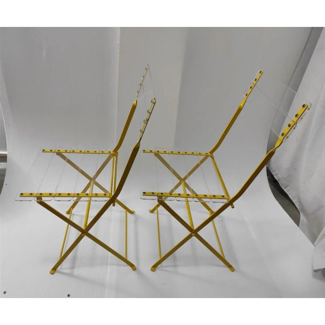 Pair of garden acrylic glass chairs with yellow metal structure. They appear to be of design and with a style attributable...