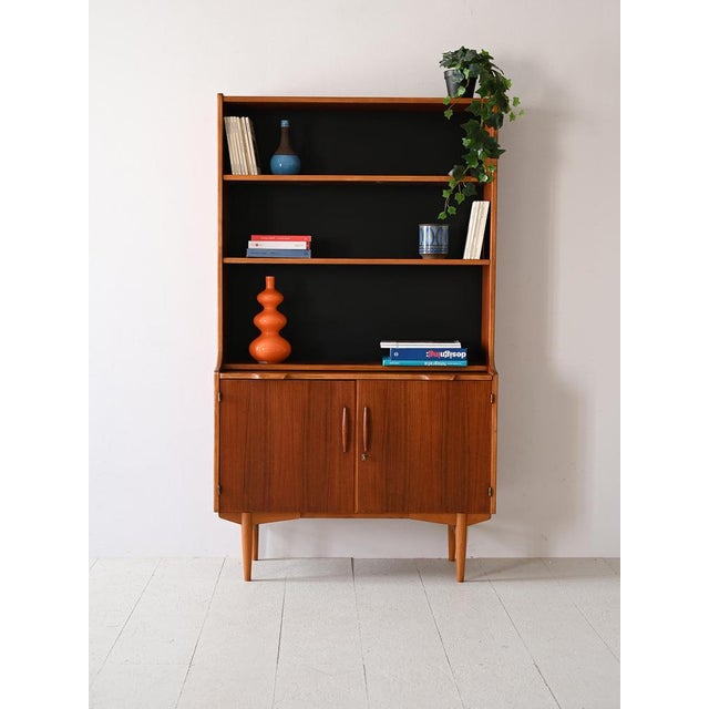 Teak cabinet with shelving and storage compartment. This Scandinavian bookcase from the 1960s, thanks to the extractable...