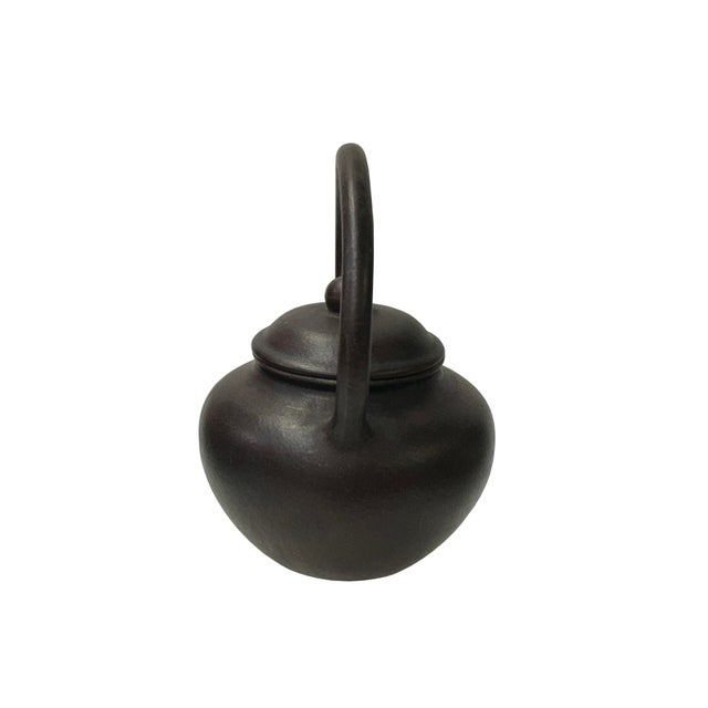 This exquisite dark clay teapot features a classic rounded body and a graceful overhead arch handle, paired with a...