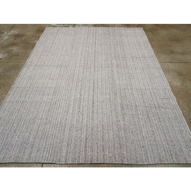 This mid-20th century Turkish flatweave kilim rug, features a subtle vertical stripe design in a soft, muted gray palette....