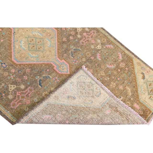 Beautiful vintage Persian distressed hand-knotted wool runner with a brown color field. This piece has multicolor accents...