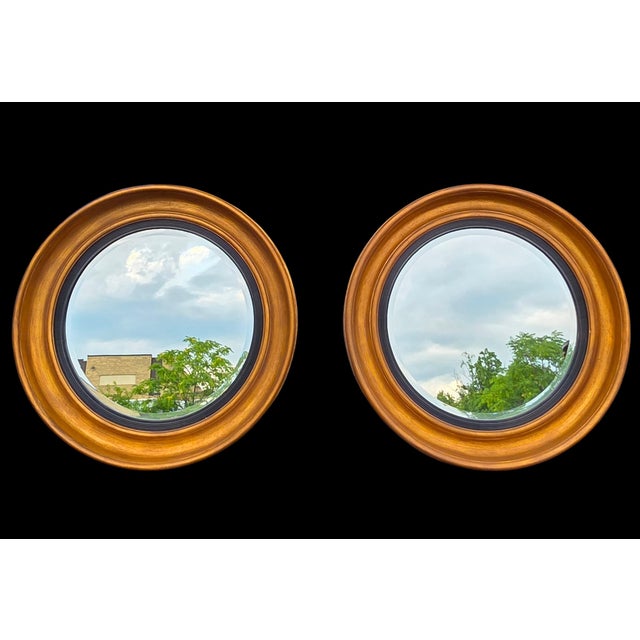 An exceptional and monumental pair of Friedman Brothers bullseye wall mirrors, masterfully crafted with richly toned...