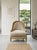The image shows a classic Louis XVI-style gilded accent armchair (or bergère) featuring a rounded back, neutral cream-...