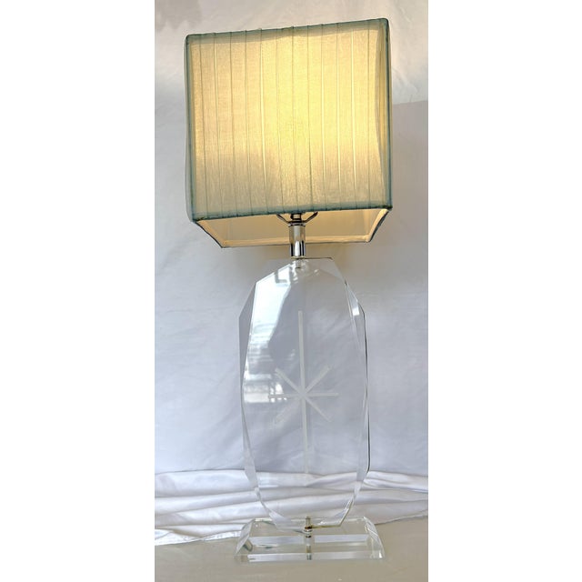 Stylish vintage lucite table lamp from the 1970's. The flat body has a faceted edge and starburst center etching and sits...