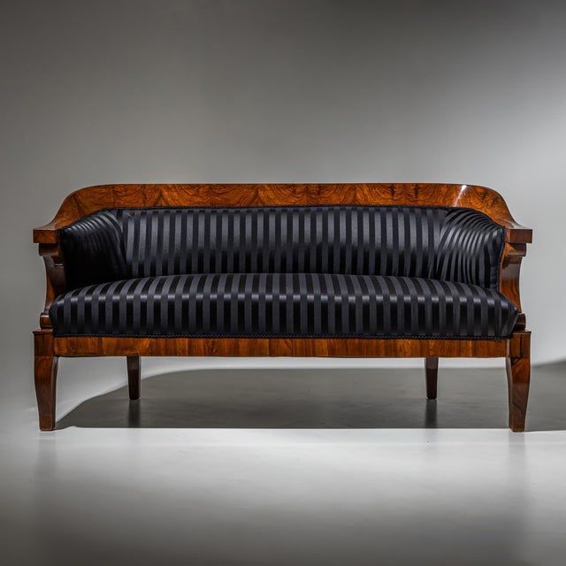 Large Biedermeier sofa raised on four slightly curved square legs, featuring a rounded backrest that terminates in...