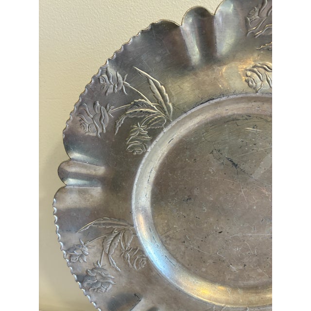 This round hammered aluminum tray features a hand-chased rose motif worked into a wide, ruffled scalloped rim, in the...