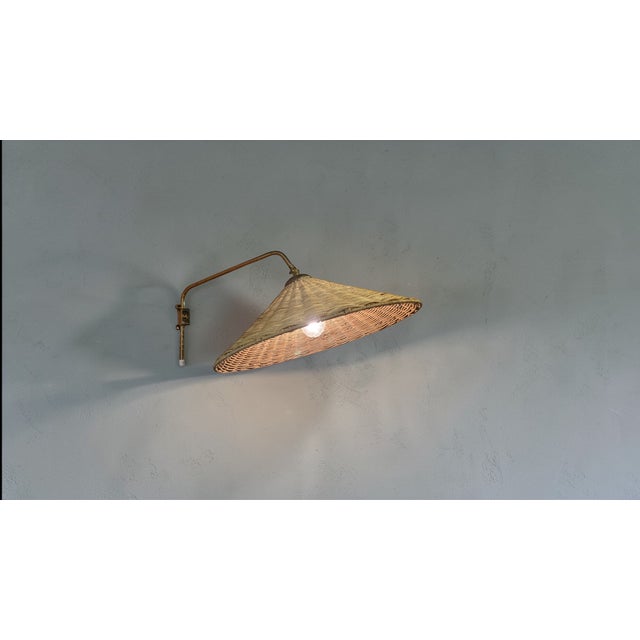 This vintage wall lamp, made by Valinte in the 1950s, beautifully combines brass and rattan into a warm and inviting...