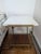 This end table features a white top and a gold wire metal frame. This table is great for placing next to a sofa or bed.