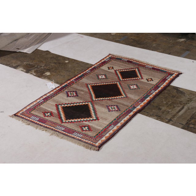 Hand-knotted in wool originating circa 1920-1930, this antique Persian rug connotes a tribal Gabbeh rug design marrying a...