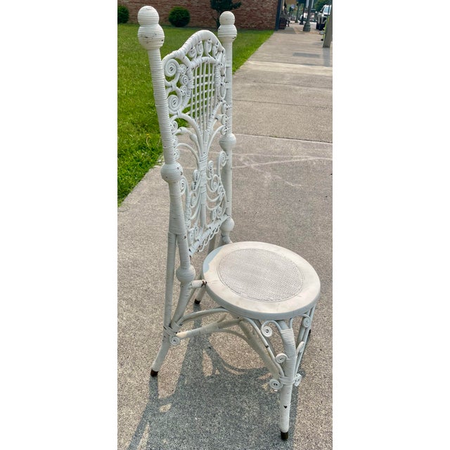 This is an ornate Victorian wicker chair with a narrow, tall back that would be perfect for a vanity, a writing desk, on a...