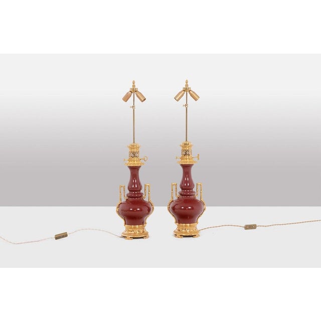 Pair of "sang-de-boeuf" colored porcelain lamps, basiluster shaped. Gilt bronze molding, base and top. Godron. Beaded...